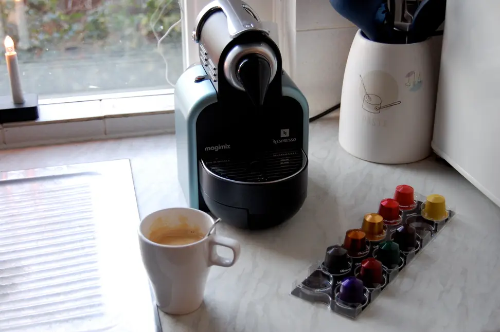 A Nespresso coffee maker with pods and cup of coffee