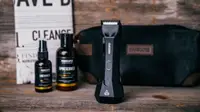 The contents of the Manscaped Perfect Package, which includes the trimmer, two bottles of product, a fake newspaper, and a toiletry bag.