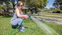 Une personne arrosant l’herbe avec un tuyau d’arrosage