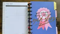ADHD planner opened to showcase colorful calendar page on top of wooden surface.
