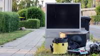 A TV sitting in a trash pile on the curb
