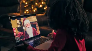 A young child looking at a laptop showing an image of Santa Claus.