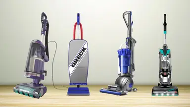 Four vacuums on a wooden floor in front of a wall