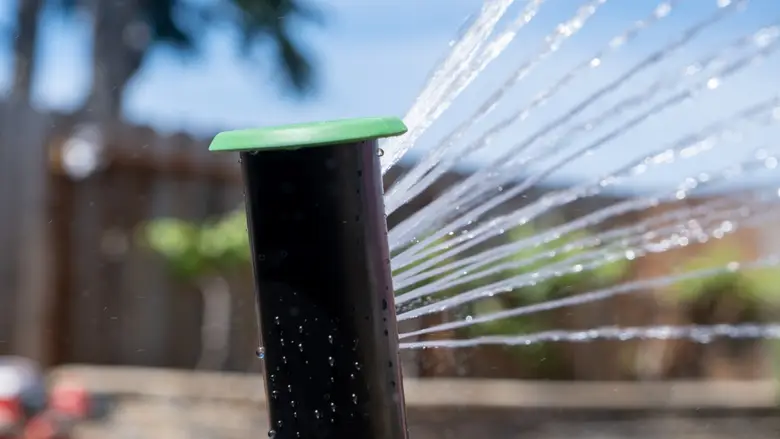 A sprinkler sprays water onto a green lawn.