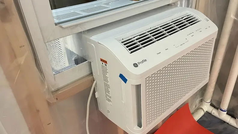 The GE Clearview, one of the best window air conditioners, appears in the Reviewed lab, installed into a window frame for testing.