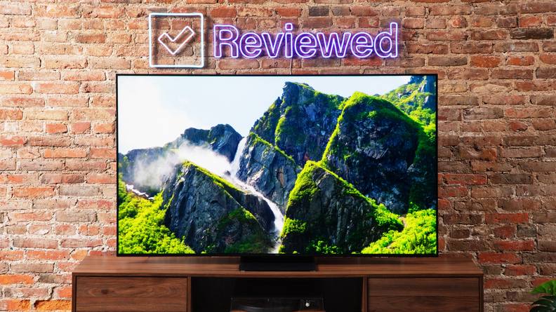 A TCL QM8 LED TV showing a colorful image of green mountains.