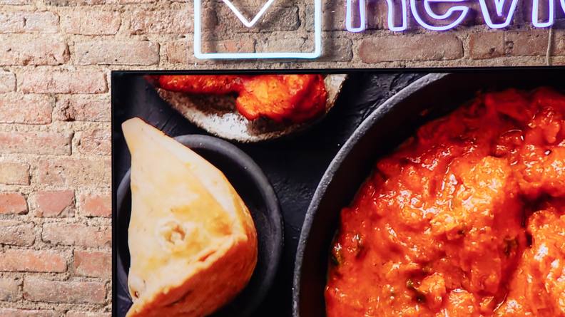 A TCL QM8 LED TV showing food being cooked onscreen with vibrant colors.