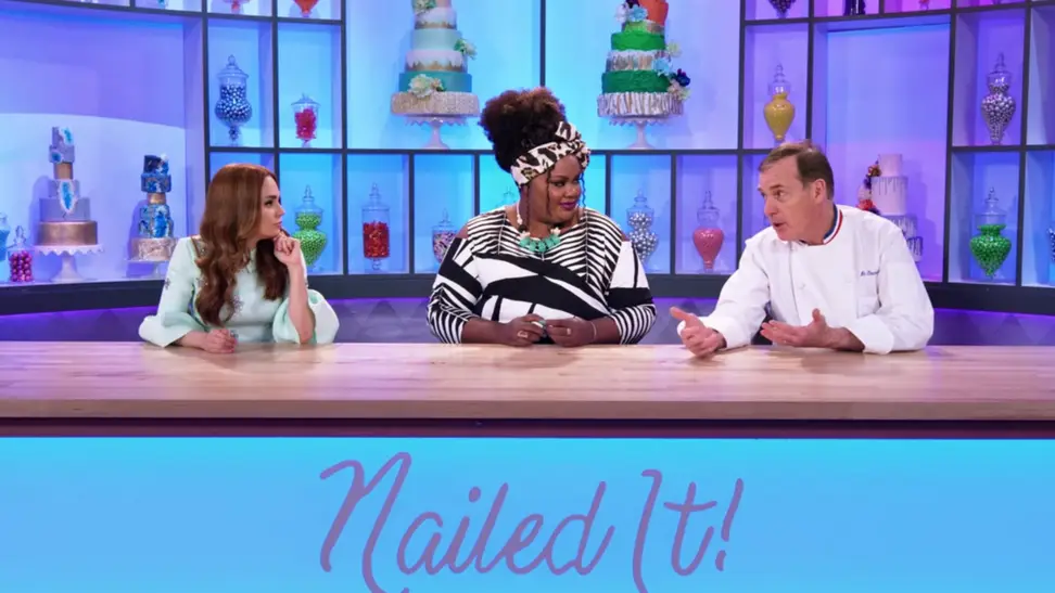 A still from the series Nailed It! featuring host Nicole Byer and Jacques Torres at the judge's table.