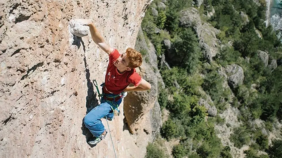A person climbing a rock wall in his climbing harness.